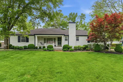 a front view of a house with a yard and trees