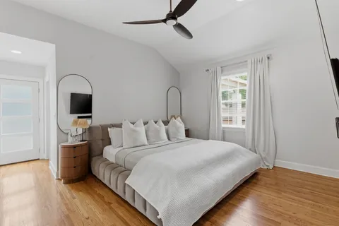 a bedroom with a large bed and a flat tv screen on dresser