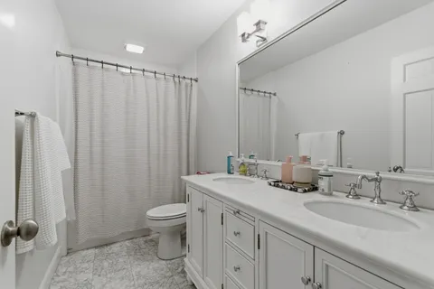 a bathroom with a double vanity sink toilet and a mirror