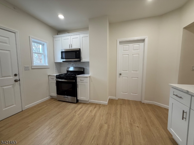 356 Carnegie Place, Unit 1 Union, NJ 07088 - Photo 4 of 10 a kitchen with granite countertop a stove top oven a sink and a microwave
