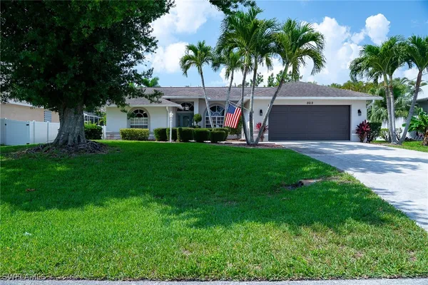 a front view of a house with a garden and palm trees