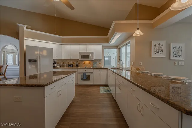 a large kitchen with stainless steel appliances granite countertop a sink and cabinets