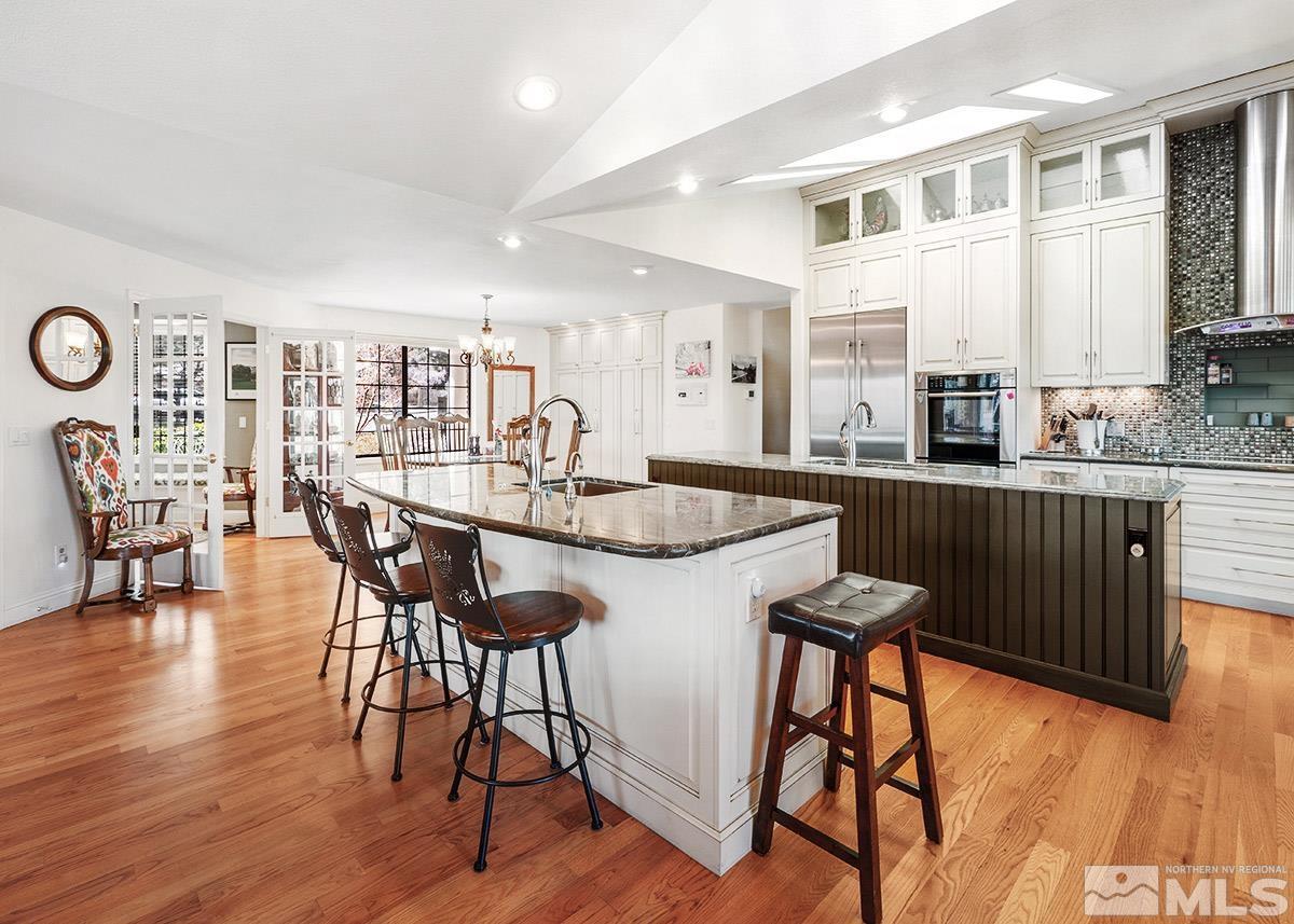2215 Hedgewood Drive Reno, NV 89509 - Photo 11 of 39 a kitchen with stainless steel appliances granite countertop a table chairs stove and wooden floor