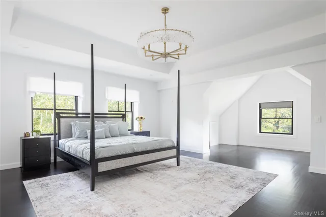 a bedroom with a bed a chandelier and large window