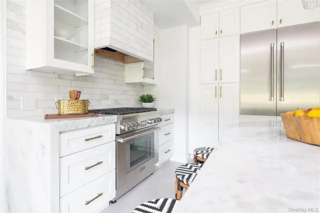 a kitchen with stainless steel appliances granite countertop a stove a refrigerator and a white cabinets
