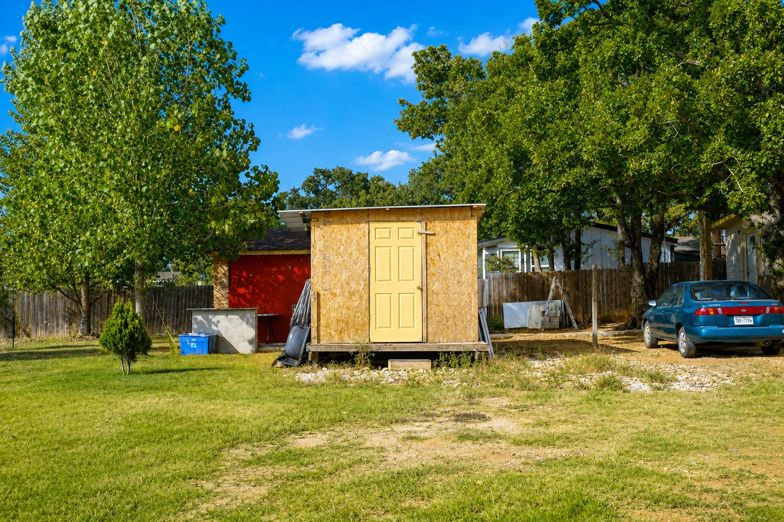 158 Buena Fortuna Road Elgin, TX 78621 - Photo 37 of 40 A quaint backyard shed, nestled amidst verdant trees and a spacious yard, offers practical outdoor storage.