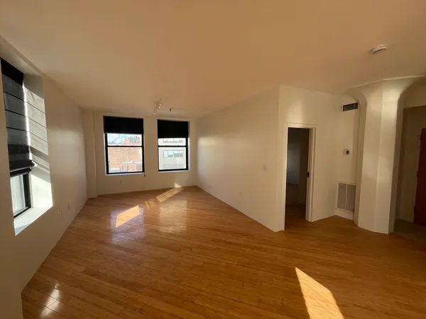 an empty room with wooden floor and windows