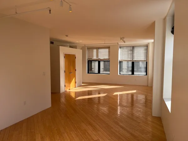 a view of an empty room with window and wooden floor