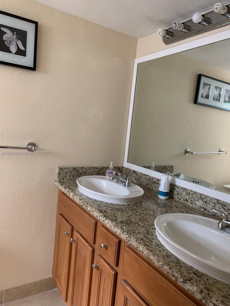 7530 Southwest 82nd Street, Unit G102 Miami, FL 33143 - Photo 6 of 9 a bathroom with a granite countertop sink and a mirror