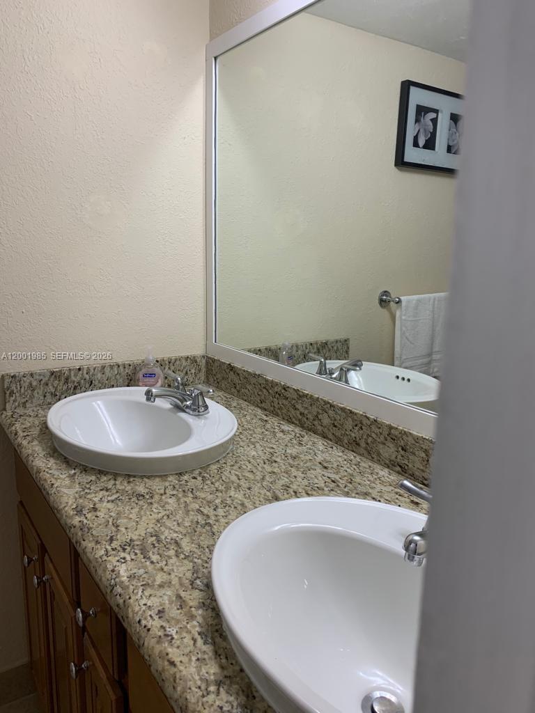 7530 Southwest 82nd Street, Unit G102 Miami, FL 33143 - Photo 7 of 9 a bathroom with a granite countertop sink and a mirror