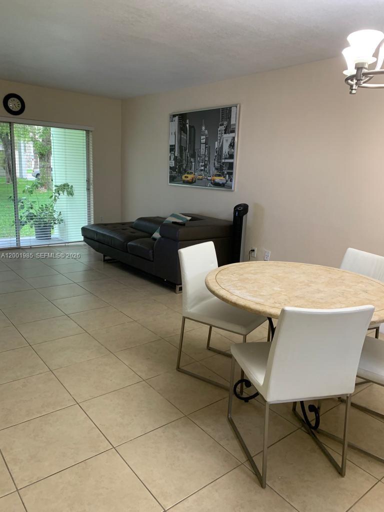 7530 Southwest 82nd Street, Unit G102 Miami, FL 33143 - Photo 9 of 9 a living room with a table chair and a large window