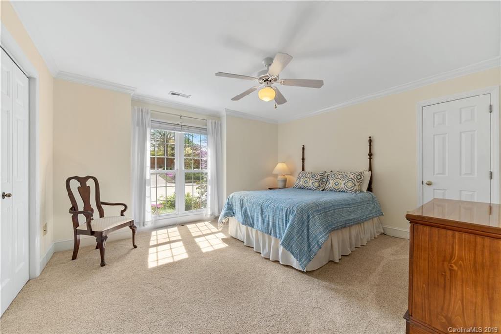 445 Cranborne Chase Fort Mill, SC 29708 - Photo 18 of 33 a spacious bedroom with a bed a chair and a chandelier