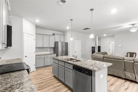 a kitchen with stainless steel appliances kitchen island granite countertop a sink a refrigerator and a stove