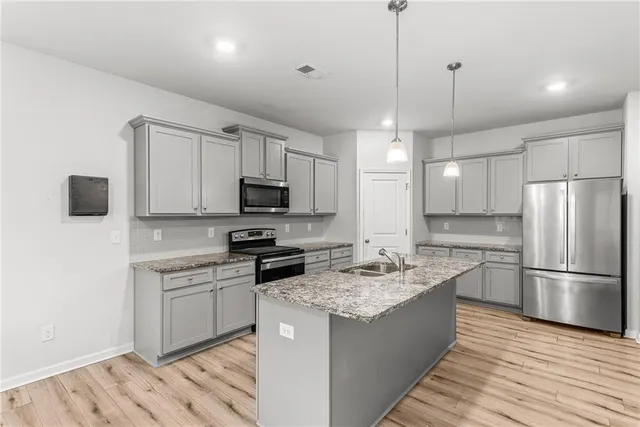 a kitchen with stainless steel appliances granite countertop a sink stove a refrigerator a center island with wooden floor and cabinets