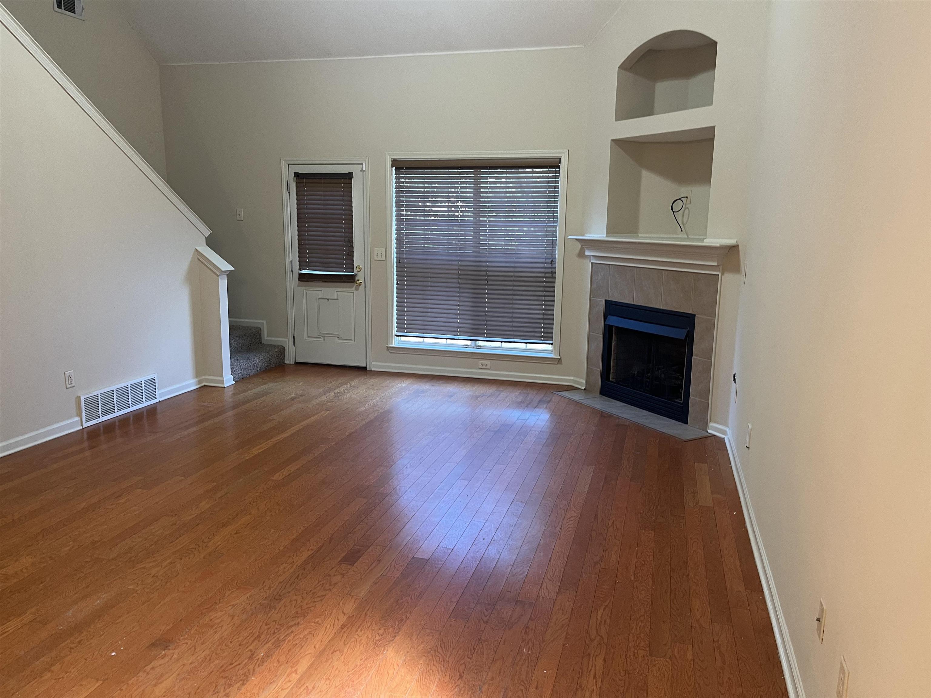 7020 Wynne Ridge Road North Cordova, TN 38016 - Photo 3 of 12 Unfurnished living room featuring stairs, wood-type flooring, a fireplace, and built in shelves