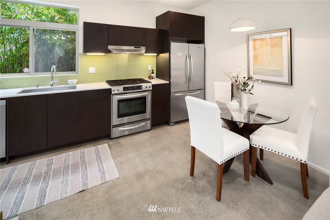 1829 24th Avenue, Unit A Seattle, WA 98122 - Photo 6 of 25 a kitchen with stainless steel appliances kitchen island a table chairs in it and wooden floor