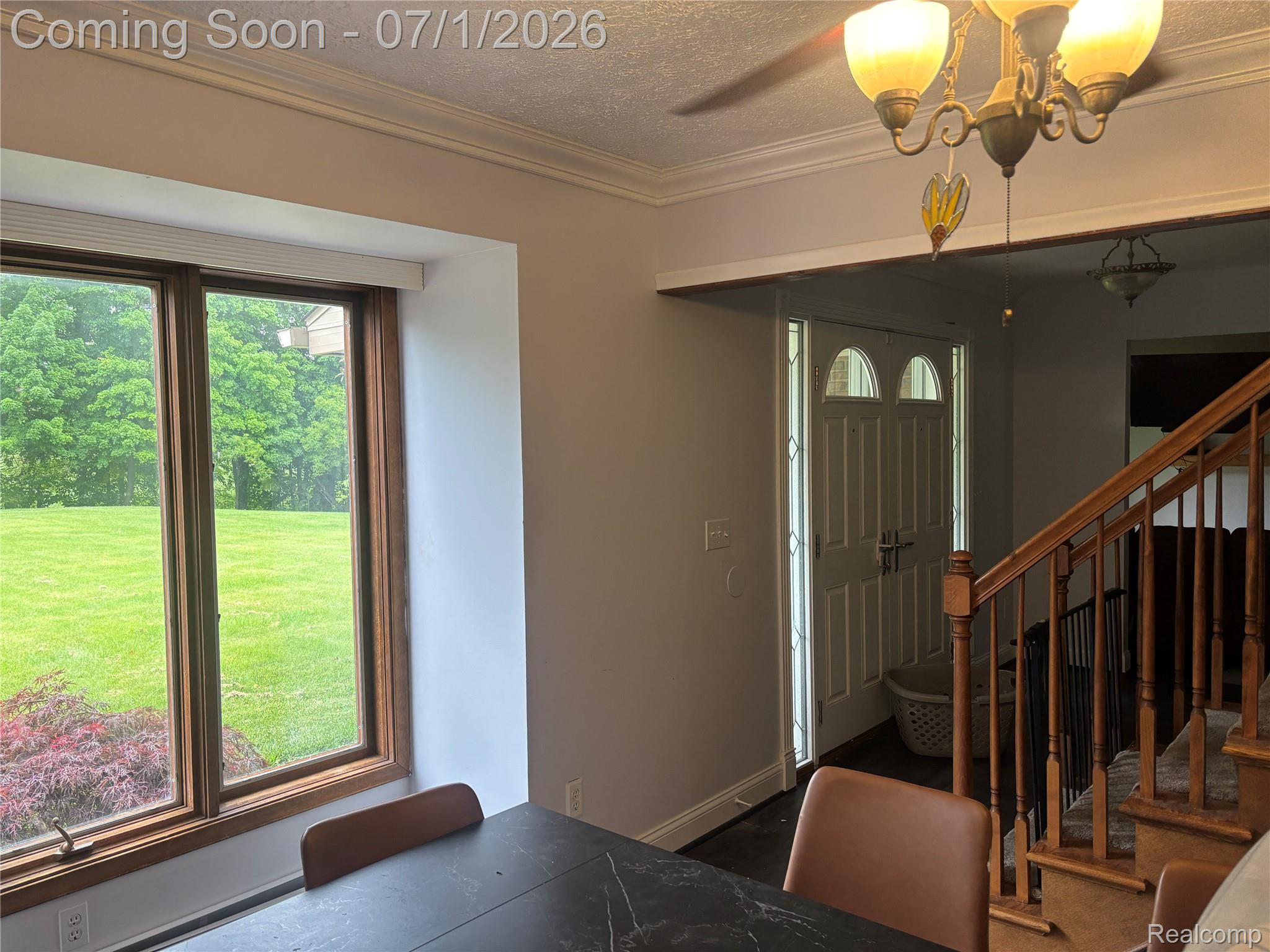 9844 Pine Knob Road Clarkston, MI 48348 - Photo 11 of 15 Bright interior featuring a large picture window with wood-finish trim, a paneled front door with sidelights, a wood-finish staircase, and crown molding