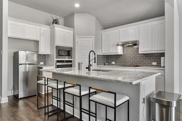 a kitchen with stainless steel appliances granite countertop a white cabinets and a refrigerator