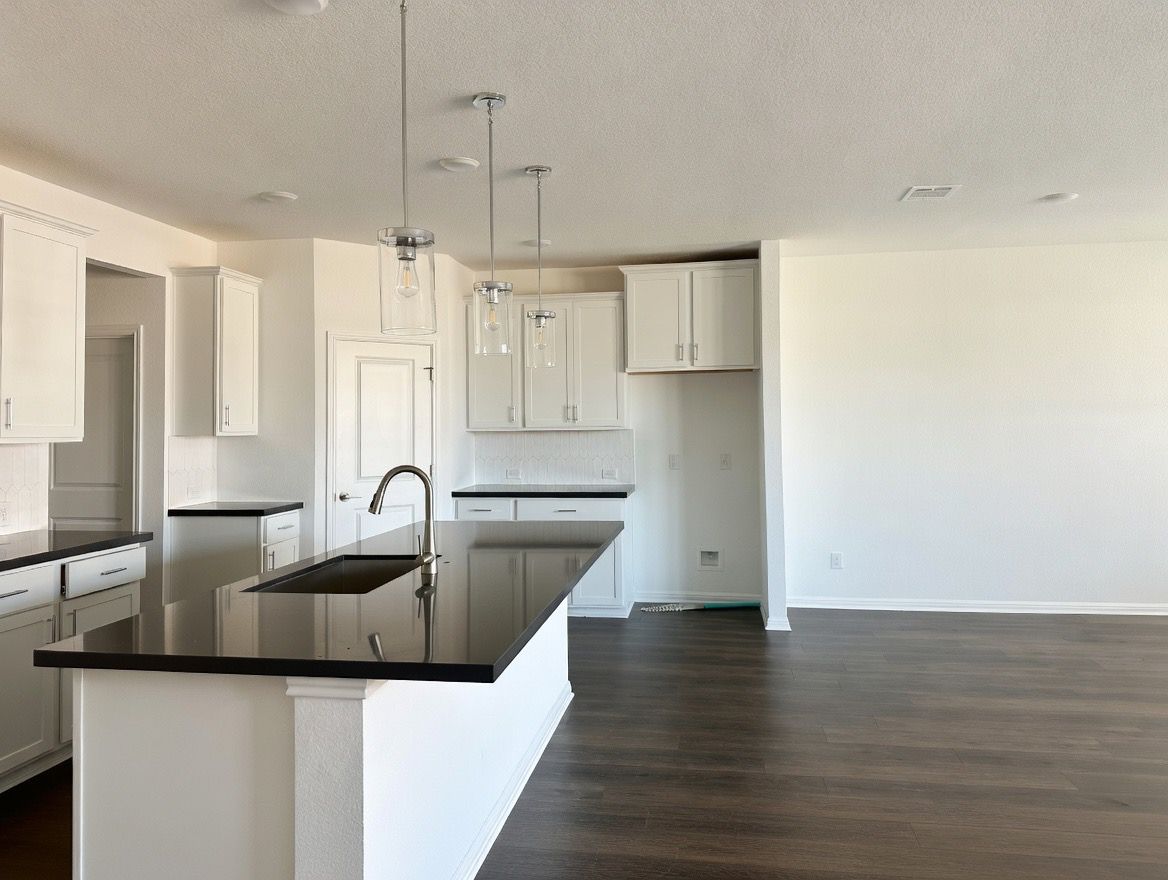 4002 Wynn Road Hutto, TX 78634 - Photo 24 of 29 Kitchen with an island with sink, dark wood-type flooring, white cabinetry, a textured ceiling, and hanging light fixtures