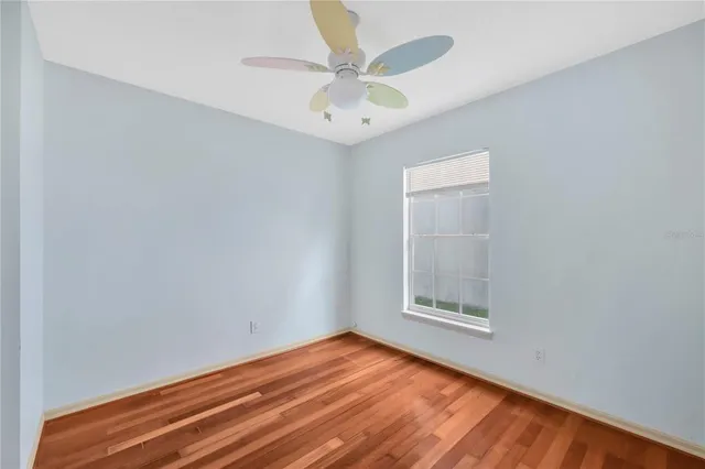 an empty room with a window and a ceiling fan