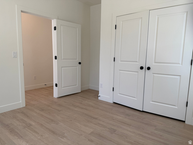 10995 South Freestone Road, Unit 109 South Jordan, UT 84009 - Photo 4 of 20 Unfurnished bedroom featuring light wood-style floors and a closet