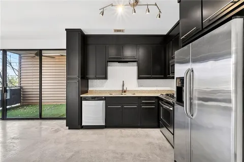 a kitchen with stainless steel appliances granite countertop a sink and a refrigerator