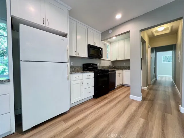 a kitchen with a refrigerator a stove top oven and wooden floor