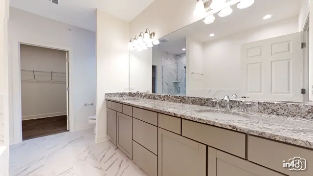 a bathroom with a granite countertop double vanity sink and a mirror