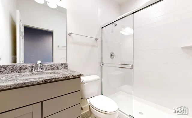 a bathroom with a granite countertop sink toilet mirror and shower