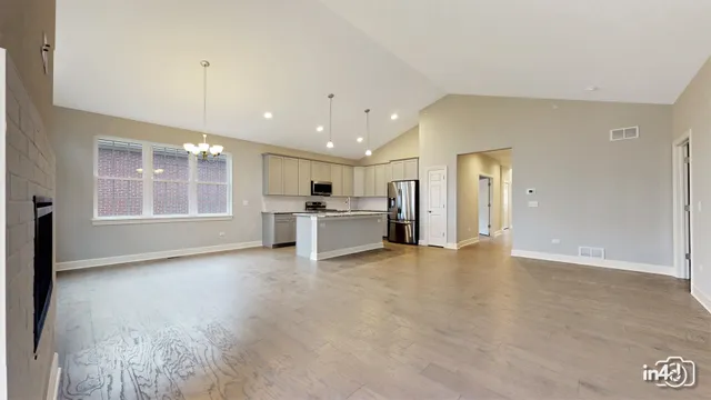 a view of an empty room with a window and kitchen view