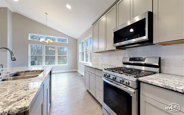 a kitchen with stainless steel appliances granite countertop a stove microwave and sink