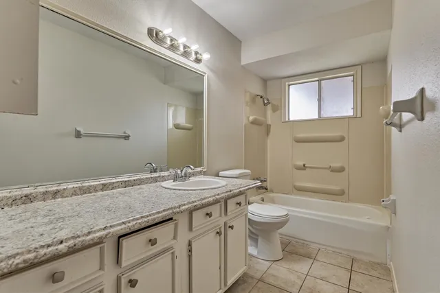 a bathroom with a granite countertop sink a toilet a mirror and shower