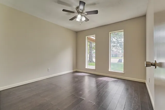 a view of an empty room with a window and wooden floor