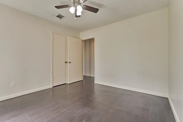 an empty room with a chandelier fan and windows