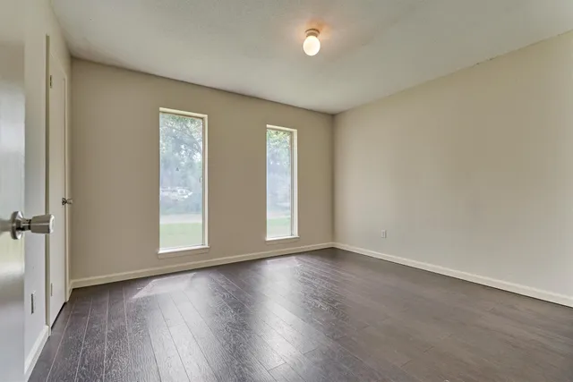 an empty room with wooden floor and windows