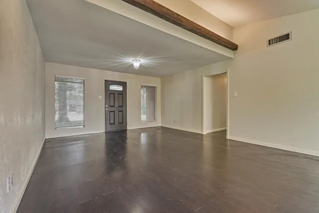 a view of an empty room with window and wooden floor