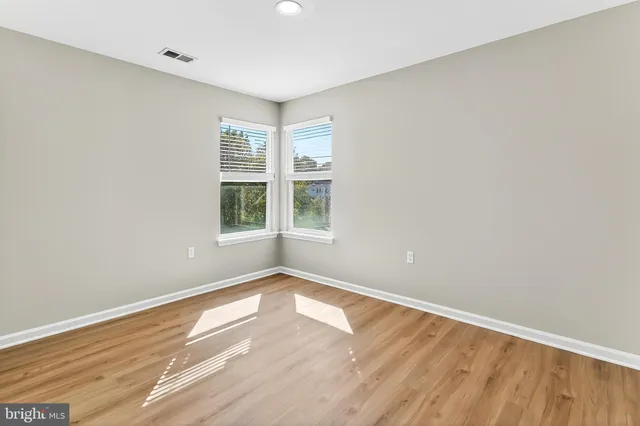 a view of an empty room with wooden floor and windows