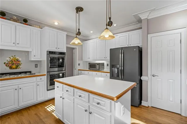 a kitchen with stainless steel appliances a refrigerator a sink and white cabinets