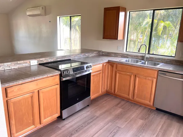 a kitchen with stainless steel appliances granite countertop wooden floors a stove a sink and a window