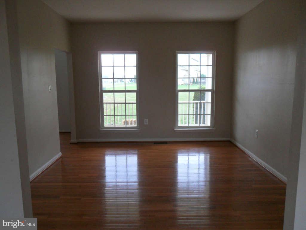 103 Ripe Berry Lane Martinsburg, WV 25403 - Photo 7 of 19 an empty room with wooden floor and windows