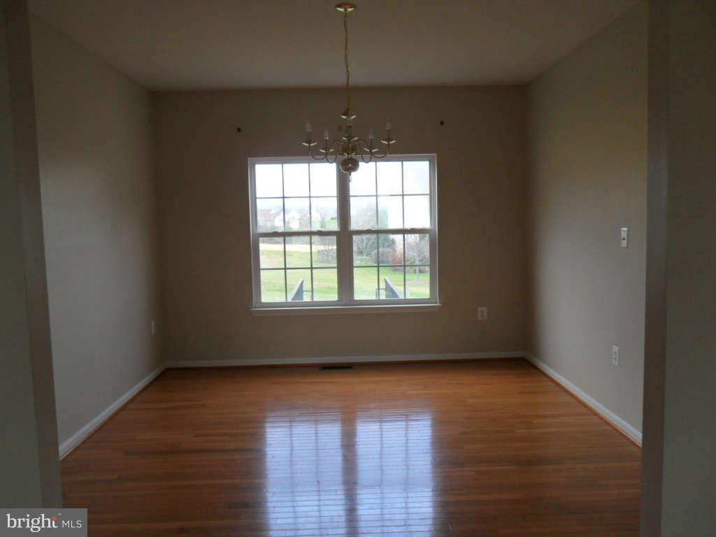 103 Ripe Berry Lane Martinsburg, WV 25403 - Photo 9 of 19 an empty room with wooden floor and windows