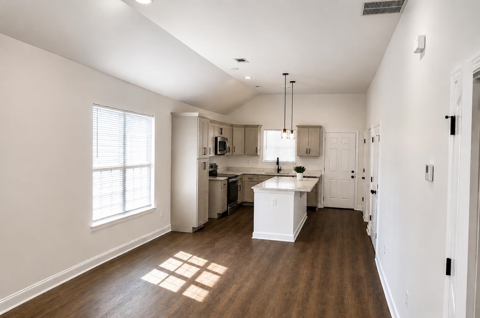 1687 East Alcy Road Memphis, TN 38114 - Photo 3 of 7 Open-concept living space featuring wood-finish flooring, a vaulted ceiling, and a kitchen with light-toned cabinetry