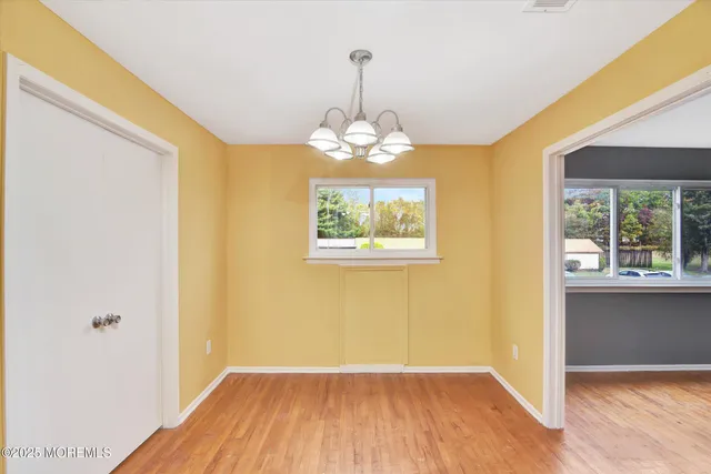 a view of a room with wooden floor chandeliers and kitchen view