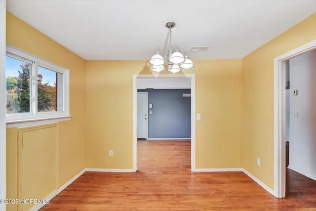 a view of a hallway with wooden floor and chandelier