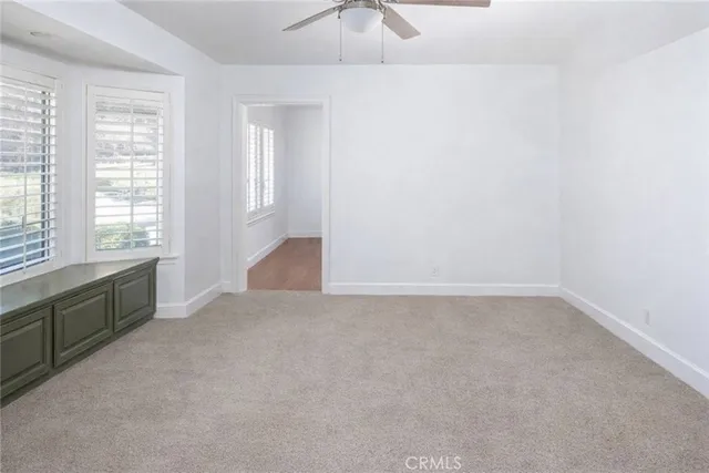 an empty room with windows and chandelier fan