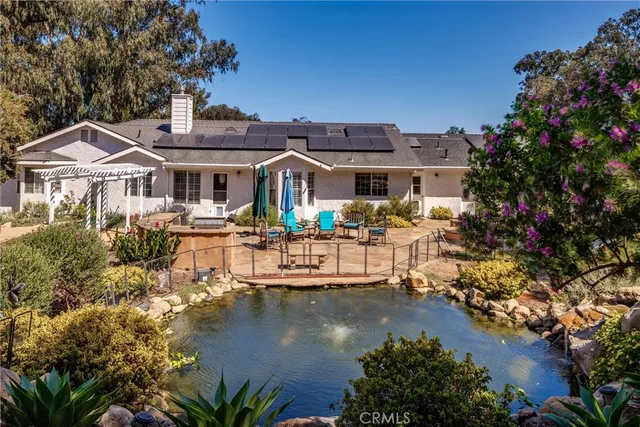 a front view of a house with lots of trees and plants