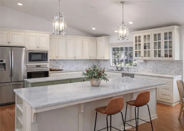 a kitchen with stainless steel appliances granite countertop a sink refrigerator and cabinets