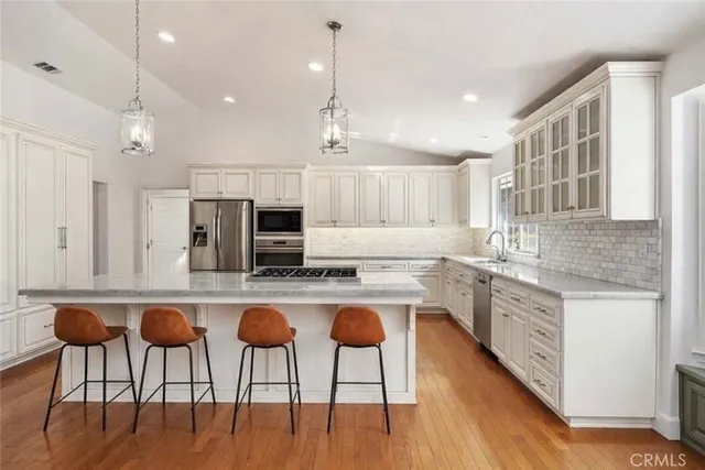 a kitchen with white cabinets and chairs