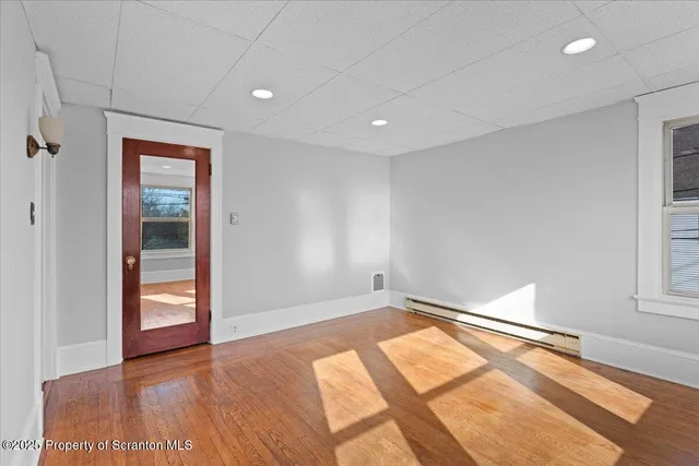 an empty room with wooden floor closet and windows