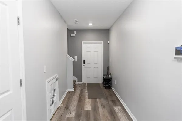a view of a hallway with wooden floor and a bathroom